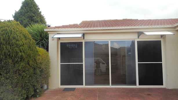 A building with a tiled roof, large sliding glass doors, and a brick pathway. - Elegant Holiday Studio (Werribee)