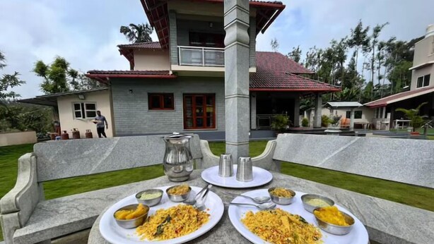 A dining table set with plates of food and condiments, a water pitcher, and a bench. - Thrilok Vihar (Chikkamagaluru)
