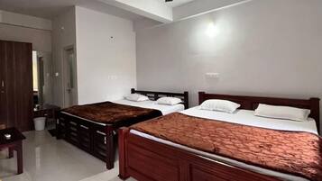 Una habitación de hotel con dos camas individuales, un armario de madera, una mesita pequeña y un ventilador de techo.