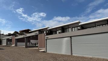 A modern building with a flat roof, large windows, and a closed roller shutter door.