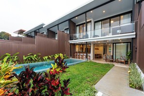 A modern two-story house with a swimming pool, a covered patio, and a well-maintained lawn.