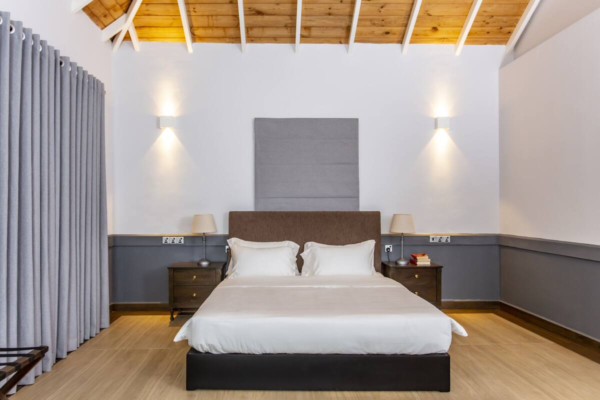 A modern bedroom with a large bed, two bedside tables with lamps, and a ceiling light fixture.