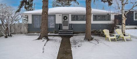 Une maison de plain-pied, dont le toit est recouvert de neige, et qui possède un porche à l’avant.