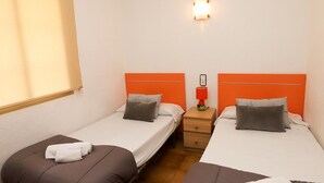 A hotel room with two single beds, each with a brown headboard and white bedding. There is a nightstand with a red lamp between the beds. - Cozy Apartment with Terrace Overlooking Pool in Vibrant Salou (Salou)