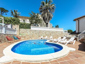 A swimming pool with lounge chairs and a stone wall.