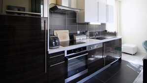Eine moderne Küche mit dunklen Schränken, einem Edelstahl-Kühlschrank, einem eingebauten Backofen und einer Mikrowelle.