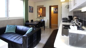 Eine moderne Wohnung mit Wohnbereich, ausgestattet mit einem schwarzen Ledersofa und einem Esstisch.