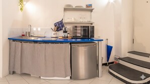 A compact kitchen with a blue countertop, a stainless steel dishwasher, and a microwave. - Home Studio Oneglia (Imperia)