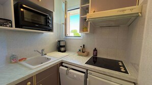 A compact kitchen with a microwave, coffee maker, sink, and dishwasher. - Cozy T2 Apartment with Parking, Pool, and City View Near Beach in Argelès-sur-Mer (Argelès-sur-Mer)