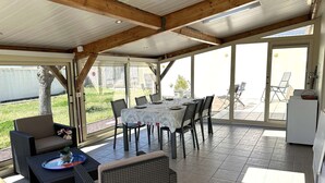 An open-plan living area with a dining table, chairs, and a sofa. - Cozy 4-room House, Sleeps 6, Near St Gilles Croix de Vie, with Garden & Veranda (Le Fenouiller)