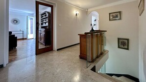 A hallway with a marble floor, a wooden staircase, and a wall-mounted light fixture. - Spacious 4-Room Apartment with Garden & Parking - Sleeps 6, Briançon (Briançon)