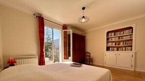A bedroom with a large bed, a wooden floor, a bookshelf, and a view of the outdoors. - Spacious 4-Room Apartment with Garden & Parking - Sleeps 6, Briançon (Briançon)