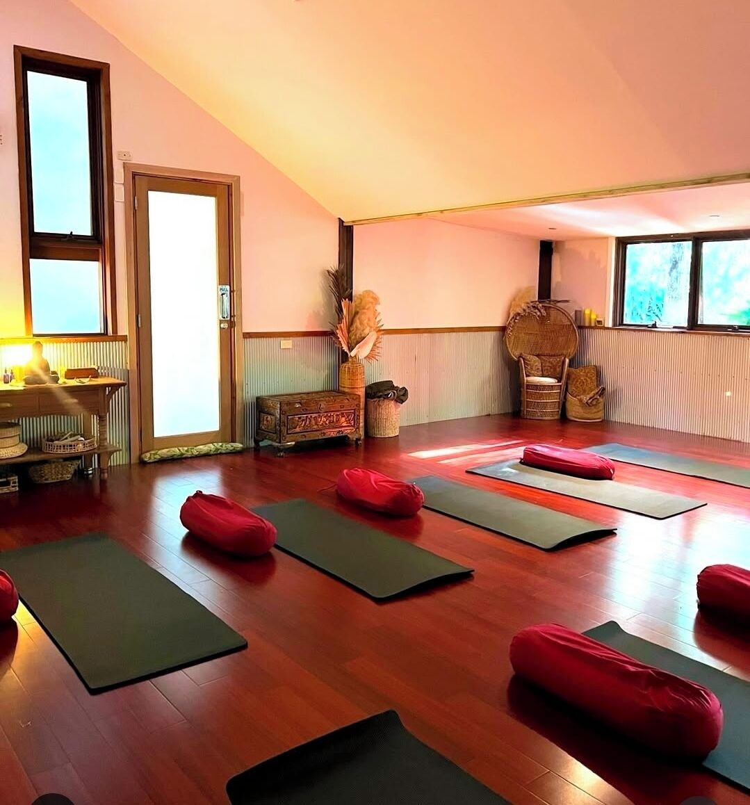 Ein Yoga-Studio mit Holzböden, Yogamatten und roten Kissen.