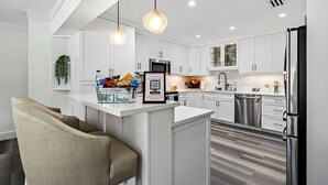 A modern kitchen with white cabinetry, a central island, stainless steel appliances, and pendant lighting.