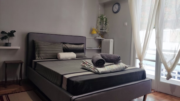 A neatly arranged bedroom with a bed, bedside table, and a small plant on a shelf. - Smart cozy apartment in Athens !!  (Athina)