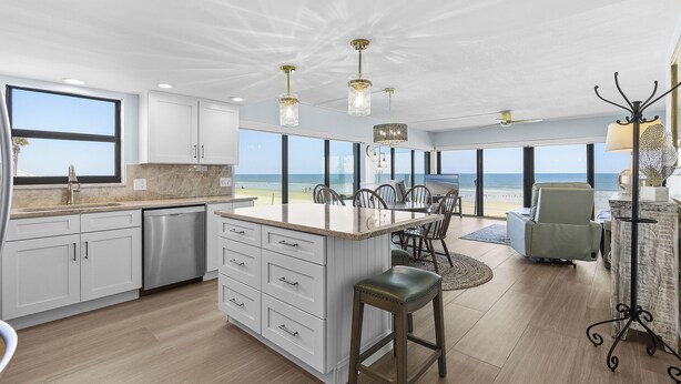 Una cocina moderna con una isla grande, armarios blancos y vistas a la playa.