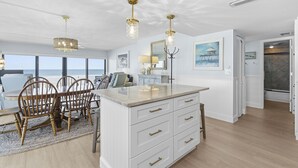 Una cocina amplia con una isla grande, armarios blancos e iluminación colgante.