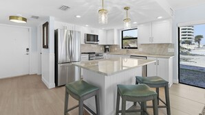 Una cocina moderna con armarios blancos, electrodomésticos de acero inoxidable y una isla grande con taburetes de bar.