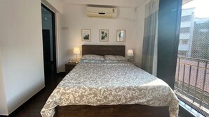 Ein Hotelzimmer mit einem großen Bett, einer Klimaanlage, einem Fenster mit Blick und einer Tür.