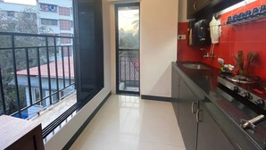 Eine moderne Küche mit roter Spritzschutzwand, einem Herd und einem Fenster mit Blick auf einen Balkon.