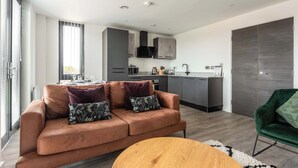 Un salon moderne avec un canapé, une table basse et une vue sur la cuisine et la salle à manger.