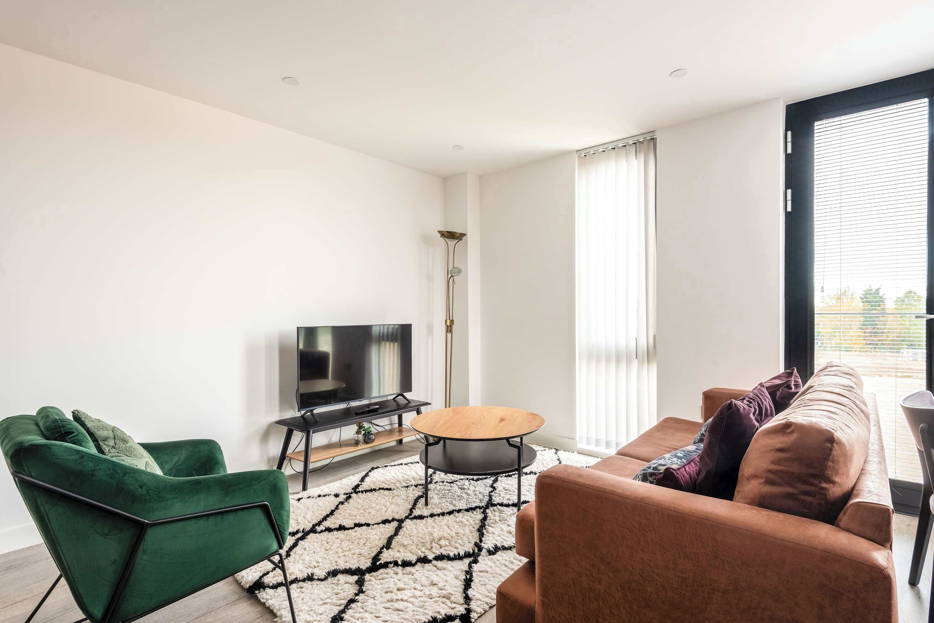 A modern living room with a green chair, brown sofa, and a wooden coffee table.