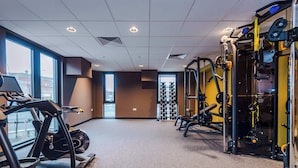 Une salle de sport équipée de machines de cardio, d’appareils de musculation et d’un porte-haltères.