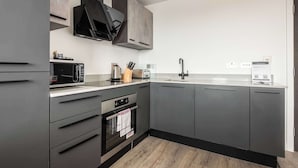 Une cuisine moderne avec des meubles gris, un four à micro-ondes, un grille-pain et un évier.