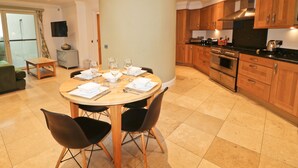 Una cocina moderna con armarios de madera, una isla central y un comedor con sillas y una mesa dispuesta para cuatro personas.
