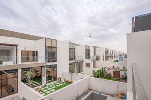A modern residential complex with multiple balconies, a rooftop garden, and a clear sky. - Zapbed Villa C62-03 (Dubai)