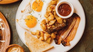 Une assiette avec des œufs, du bacon, des pommes de terre et des toasts.
