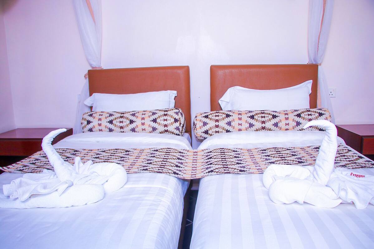 Un letto matrimoniale con biancheria decorata e due cigni fatti con asciugamani.
