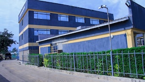 Un immeuble à plusieurs étages, doté d’une façade bleue et jaune, d’une entrée sécurisée par un portail et d’une allée pavée.