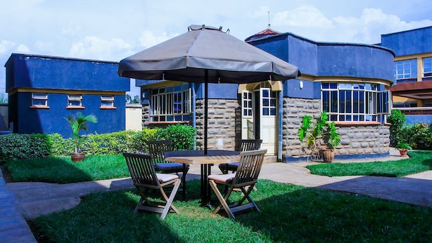 Une terrasse extérieure avec une table et des chaises, un grand parasol et un mur de pierres en arrière-plan.