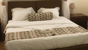 Un lit bien fait, avec une couverture à motifs, une tête de lit et une lampe de chevet.