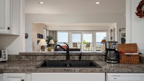 A kitchen with a granite countertop, a black sink, and a coffee maker.