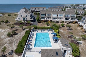 Luftaufnahme eines Strandhotels mit Schwimmbad, mehreren Balkonen und Blick auf den Ozean.