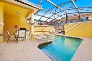 An indoor swimming pool with a glass ceiling, yellow walls, and a seating area with chairs and a table. - Pool Oasis 4BR Townhome w Theme rooms near Disney (Kissimmee)