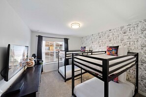 A room with bunk beds, a television, and a window with curtains. - Pool Oasis 4BR Townhome w Theme rooms near Disney (Kissimmee)