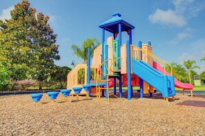 Une aire de jeux avec un toboggan, des structures d’escalade et un espace de jeux couvert.