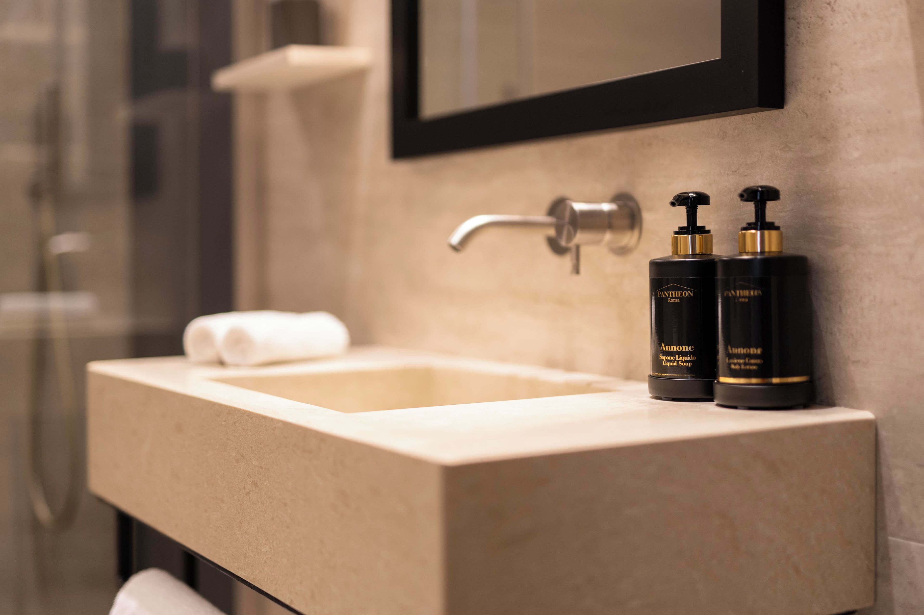 A bathroom with a sink, two bottles of soap, and a towel.