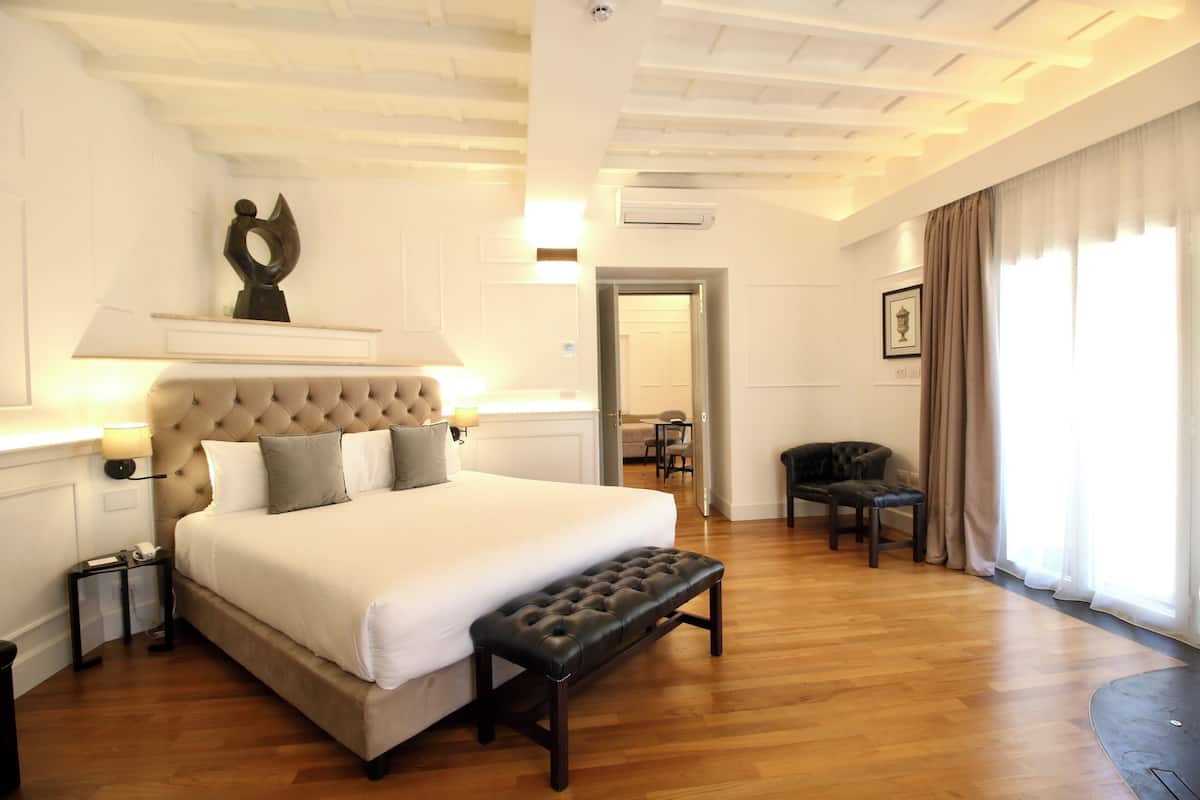 A spacious bedroom with a large bed, a bench, a desk, and a chair.