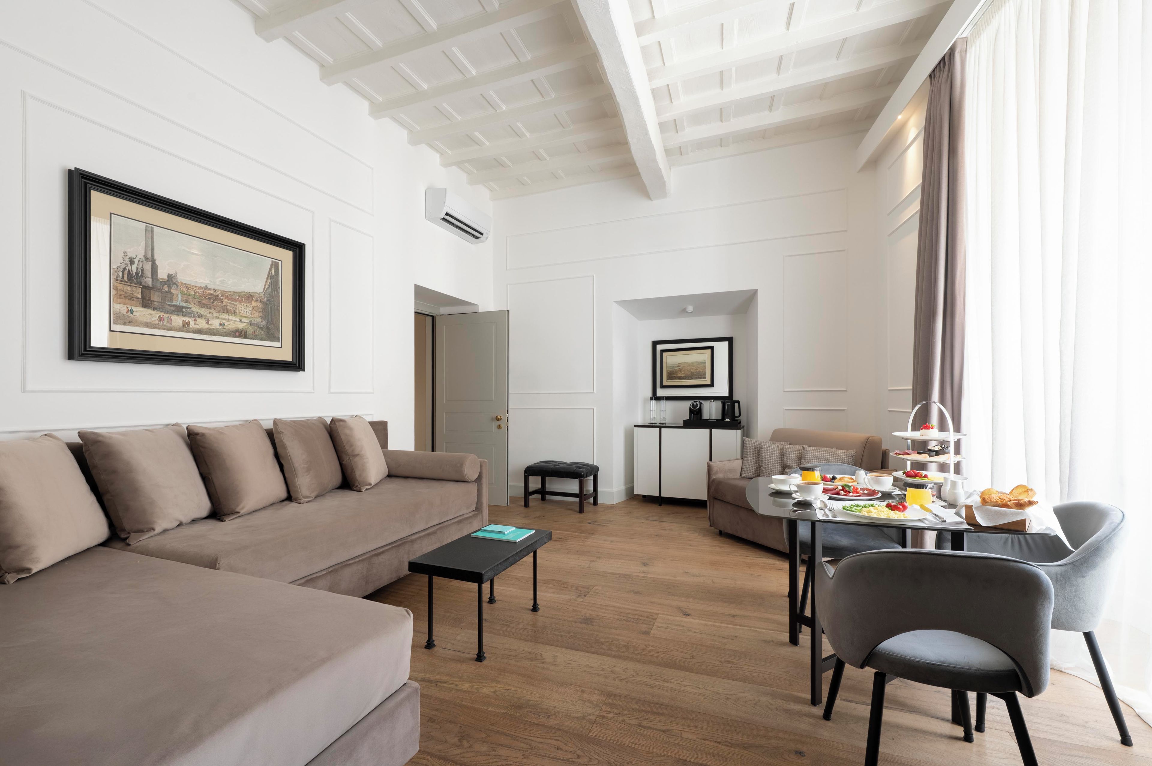 Un salon moderne avec un canapé, une table à manger dressée pour le petit-déjeuner et un tableau accroché au mur.