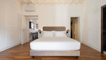 Une chambre spacieuse avec un grand lit, un plancher en bois et un plafond avec des poutres apparentes.
