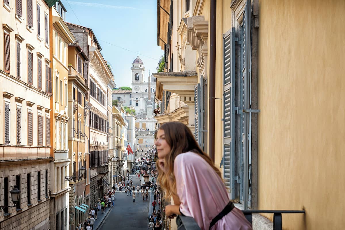 A narrow street lined with historic buildings, a central church, and a crowd of people.