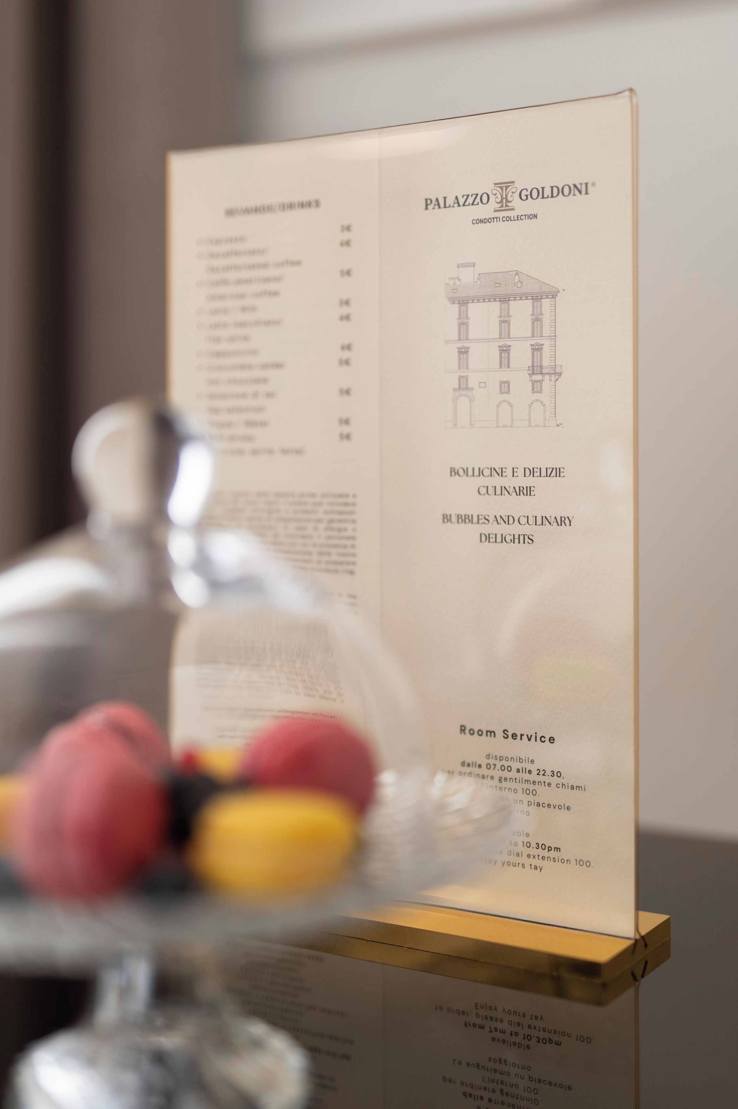 A menu board with a list of items and prices, a glass display case with pastries, and a building illustration.
