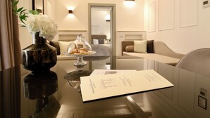 A hotel lobby with a reception desk, a vase with white flowers, a glass cake stand, and a framed menu. - Palazzo Goldoni Condotti Collection (Rome)