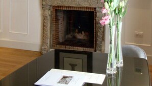 A room with a fireplace, a framed picture on the wall, and a table with a vase of flowers. - Palazzo Goldoni Condotti Collection (Rome)