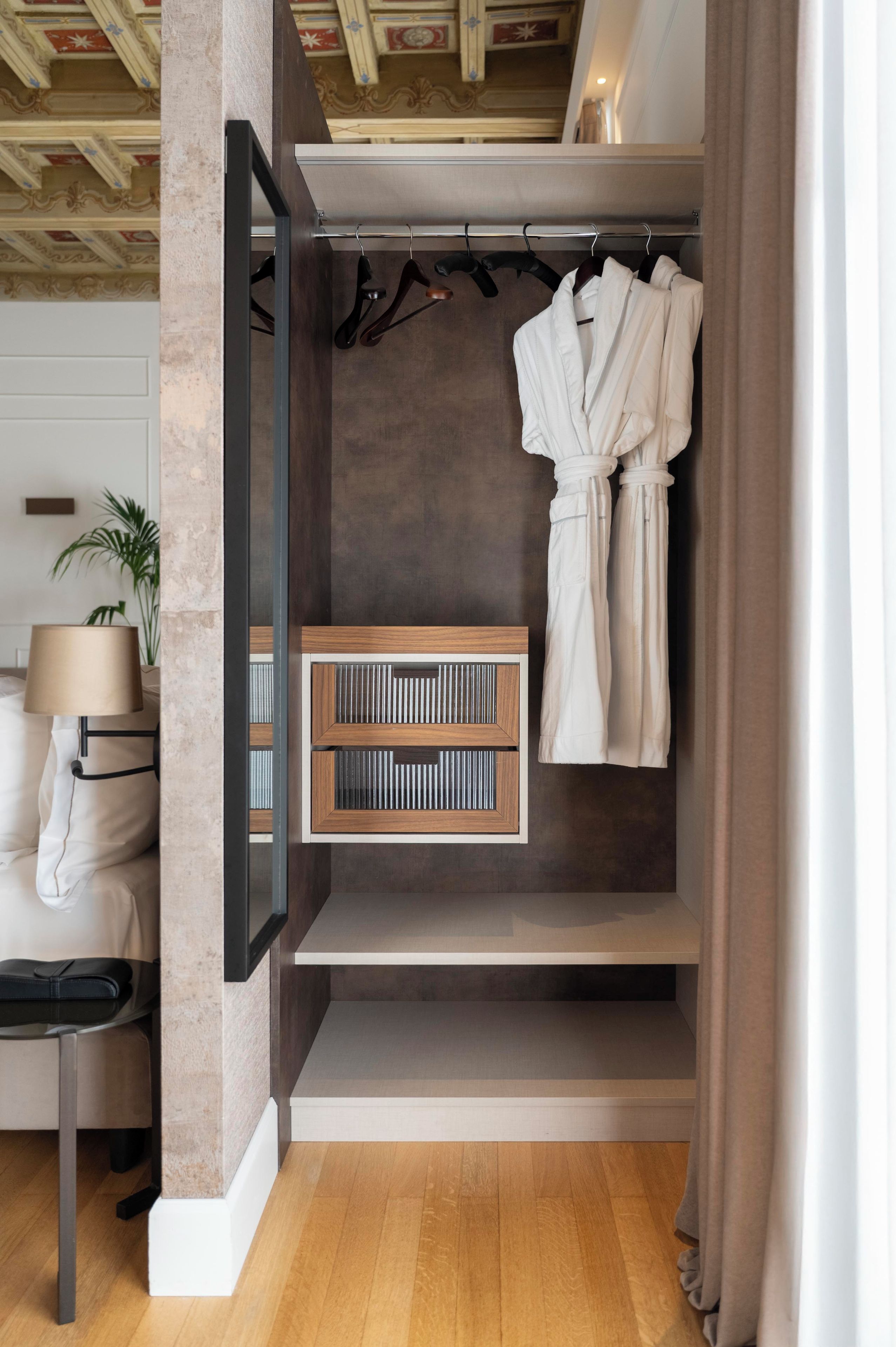 Uma casa de banho moderna com uma cómoda de madeira, suporte para roupão e uma estante embutida com livros.