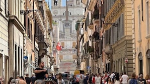 A bustling street with historic buildings, a prominent church with two towers, and a horse-drawn carriage. - Palazzo Goldoni Condotti Collection (Rome)